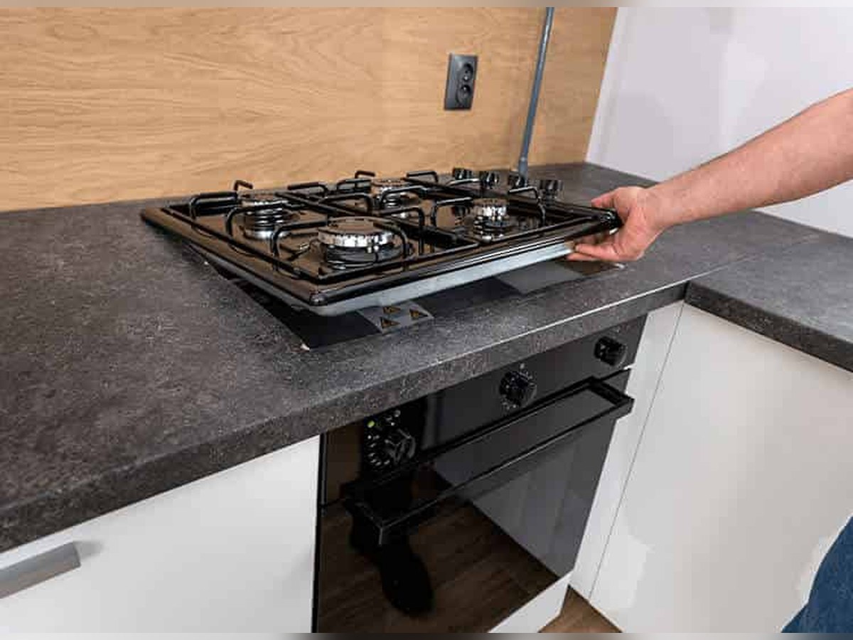 Built-in gas hob being lowered into a cut-out in a kitchen counter
